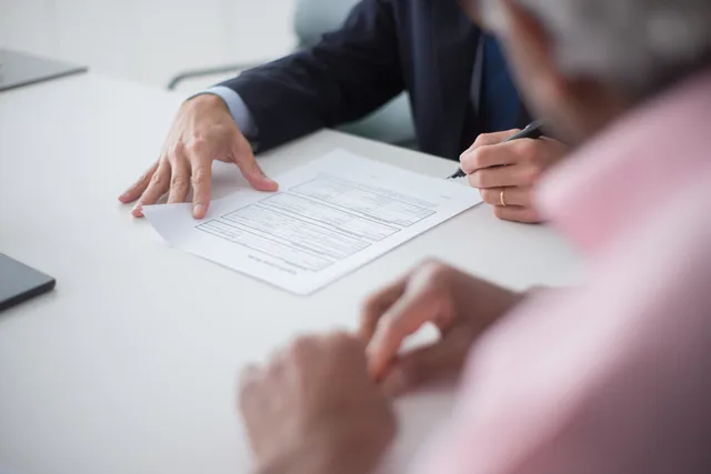 Two professionals engaging in a business meeting, signing documents for a consulting agreement. Hvordan planlægger man et leverandørskift uden driftsafbrydelser?
